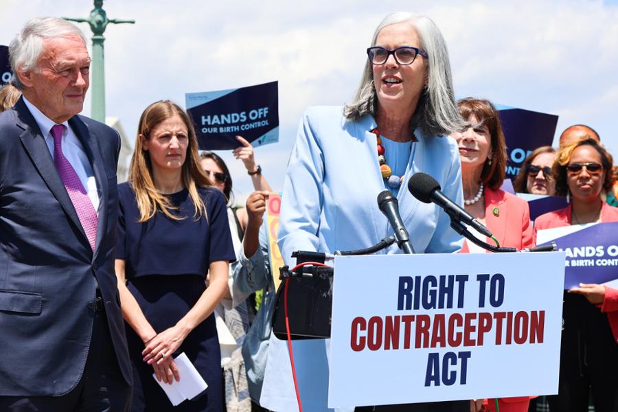 Rep. Clark speaks at a podium in front of the U.S. Capitol. The podium has a sign that says Right to Contraception Act.