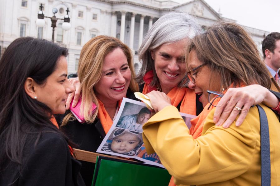 Rep. Clark hugs women who are showing her pictures of loved ones killed by gun violence.