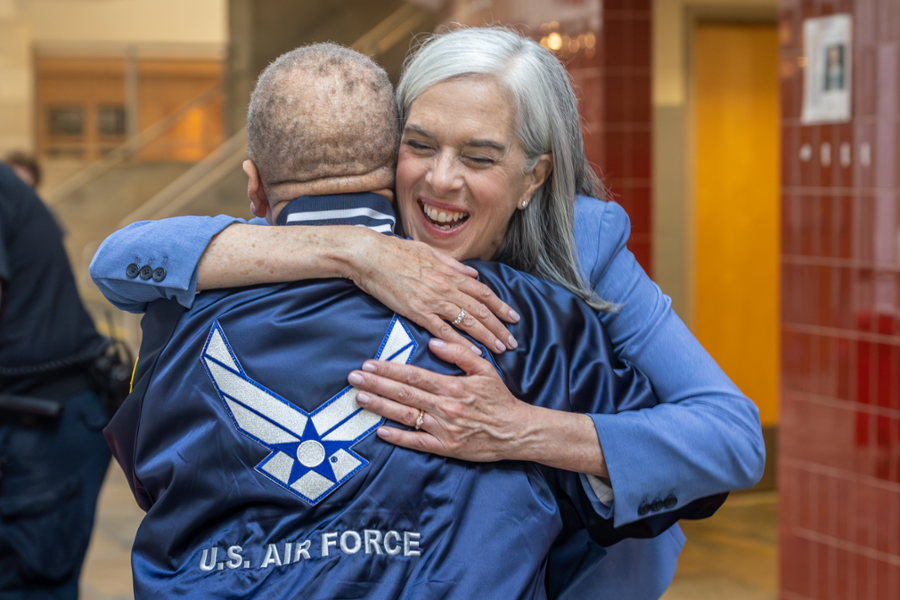 Rep. Clark hugs a man wearing an Air Force jacket at a school in Melrose.