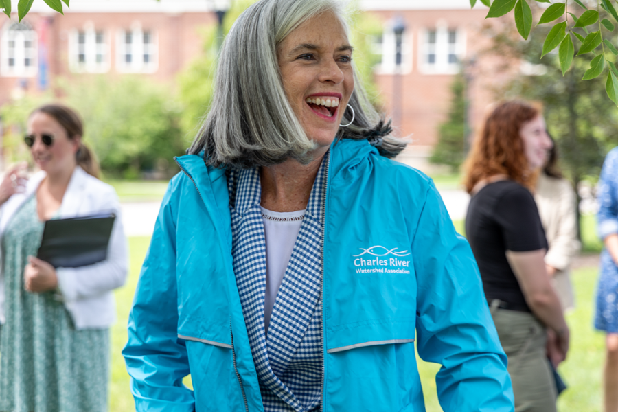 Rep. Clark laughs while wearing a blure jacket that says Charles River Watershed Association.