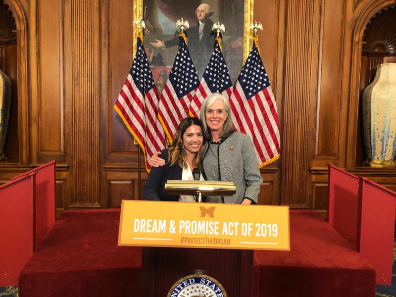 Rep. Clark poses for a picture with a constituent in front of a podium that reads Dream and Promise Act.