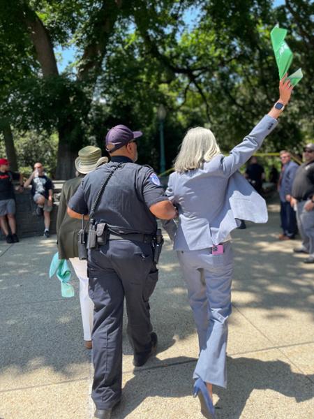 Rep. Clark waves a green cloth as she's lead away by a police officer after being arrested during a demonstration in support of reproductive freedom.