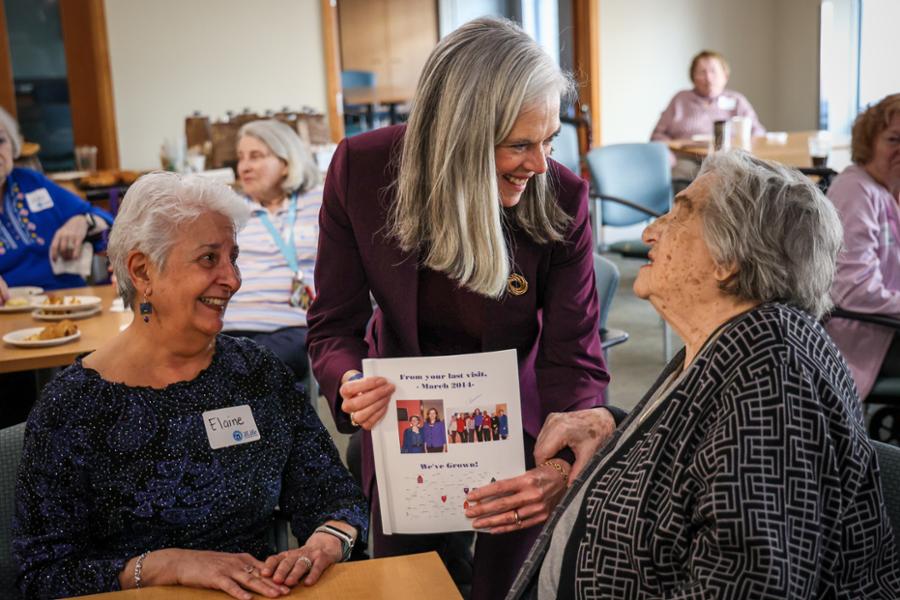 Rep. Clark leans in to speak with two elderly women in Framingham.